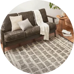 Cozy living room setup showing a dark grey leather sofa styled over a patterned cream and black area rug.