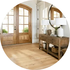Bright home entryway with light hardwood floors, a wooden console table, and glass-paned double front doors.
