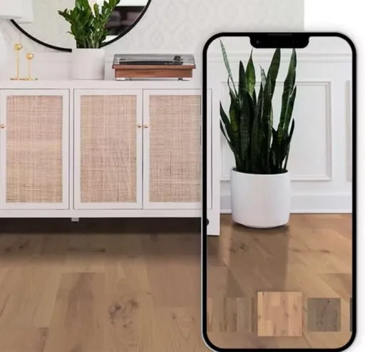 A smartphone displaying a mobile room visualizer app with flooring swatches, overlaying a modern room with hardwood floors and a white cane cabinet.