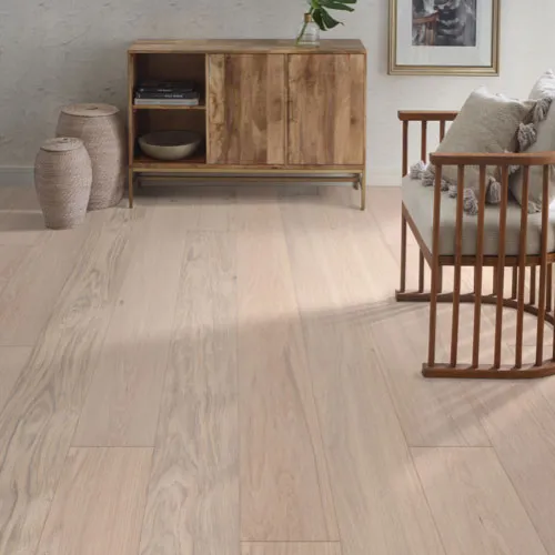 Light beige wide-plank flooring in a bright, modern room styled with a natural wood sideboard and a spindle-back armchair.